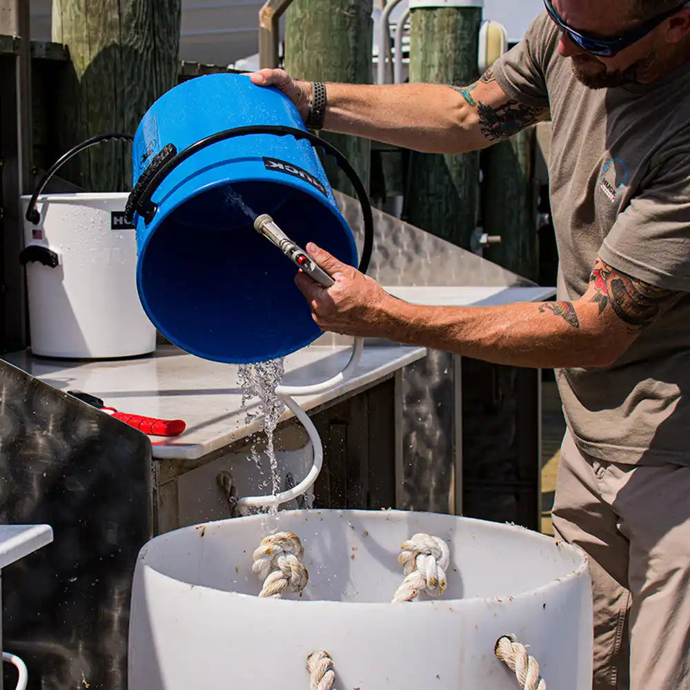 Blue plastic bucket being emptied of water.