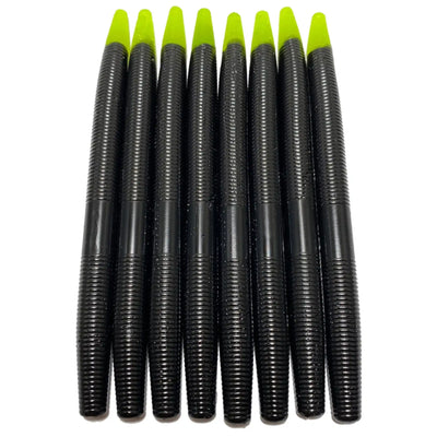 Eight black plastic fishing worms with neon yellow tips arranged in a row.