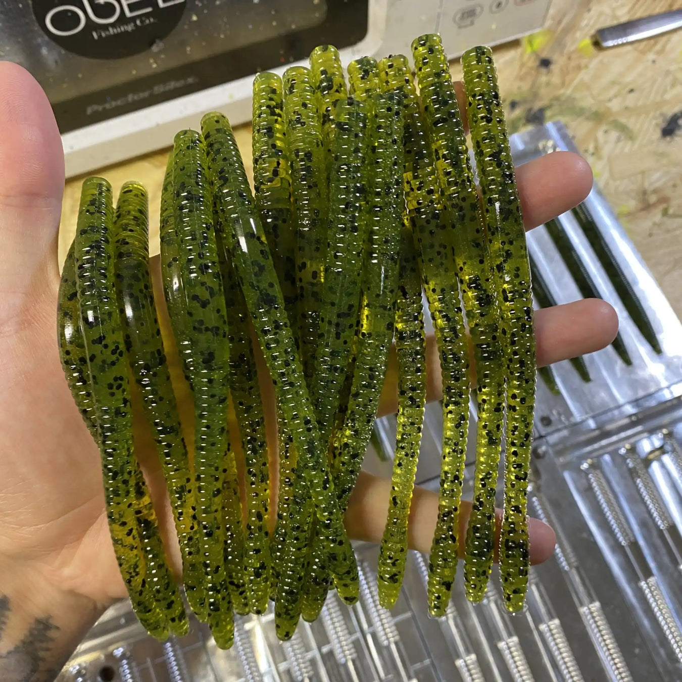 Green plastic fishing worms with ribbed texture and glitter flakes.