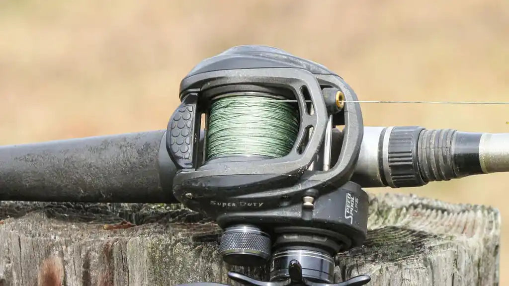 Baitcasting fishing reel mounted on a rod with green fishing line spooled on it.