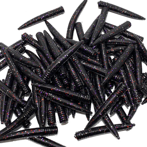 Pile of black fishing lures with red and purple glitter on a white background